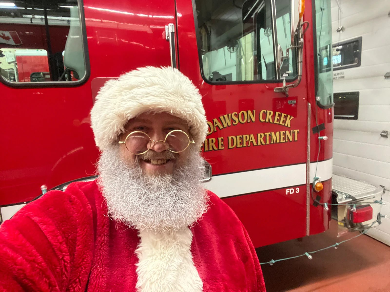 Santa Bryce smiling beside a Dawson Creek Fire Department truck